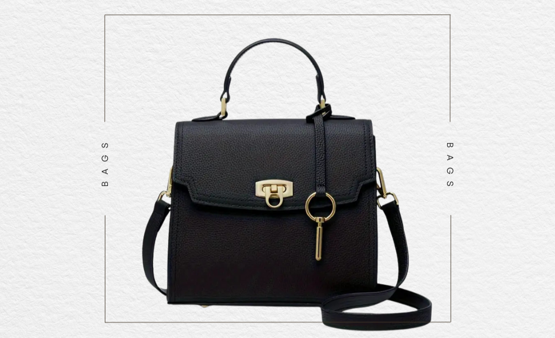 Black structured crossbody bag with gold accents on a white background, featuring 'The Sunday Club' branding.