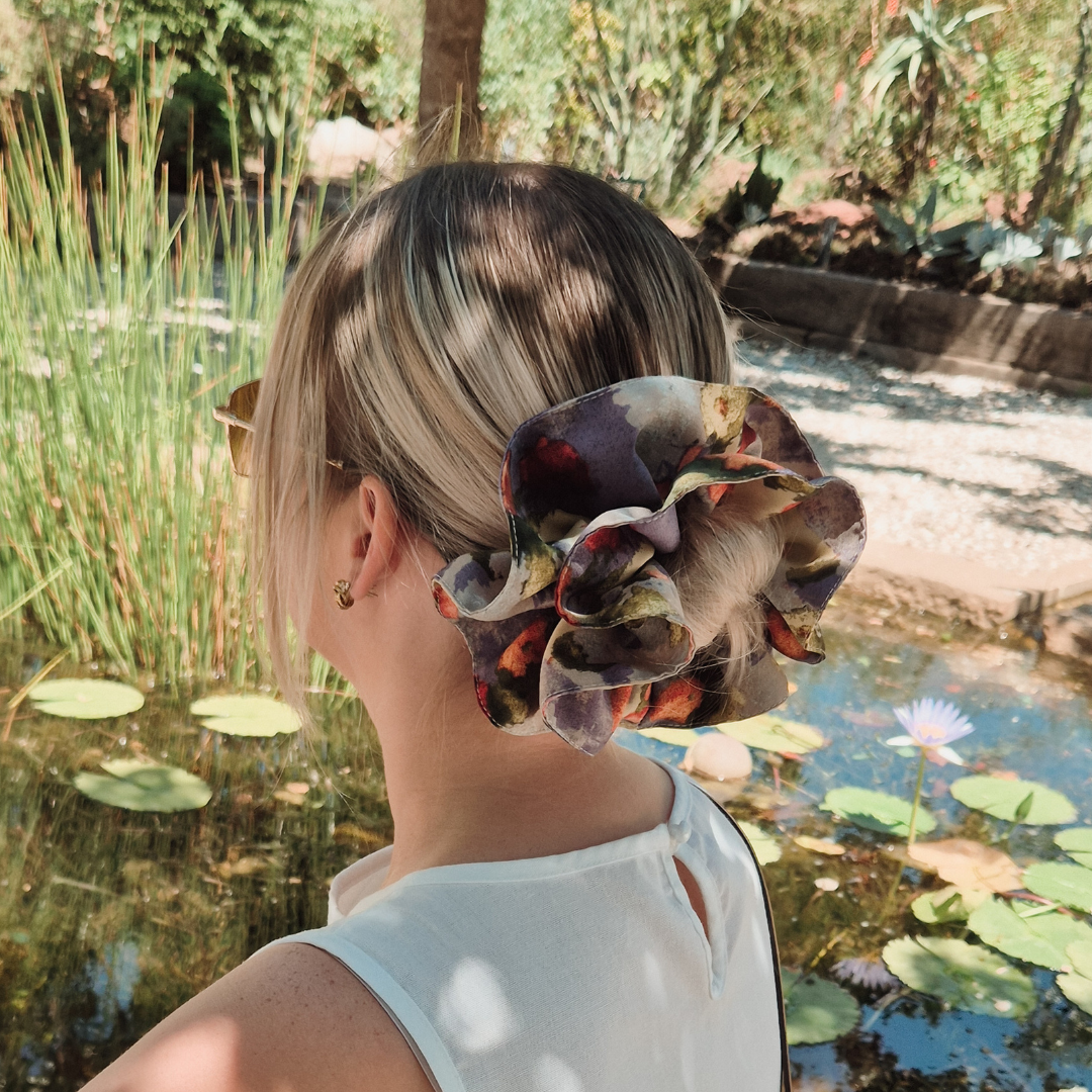 Person with a floral hair accessory standing by a pond with lily pads