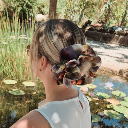 Person with a floral hair accessory standing by a pond with lily pads