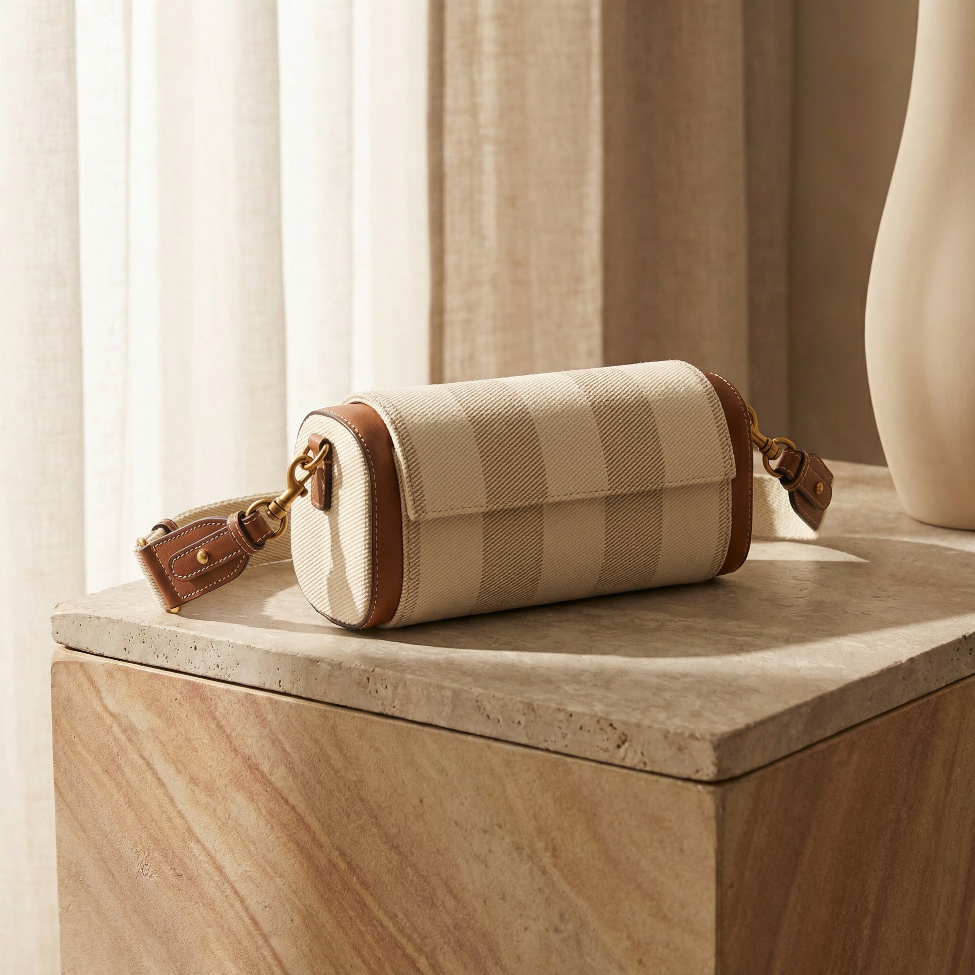 Beige checkered handbag with brown leather accents on a wooden surface with curtains in the background