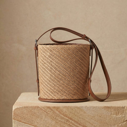 Woven handbag with leather strap on a wooden surface and beige background